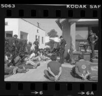 Police and 18 undocumented aliens with hands tied outside raided house in South Central Los Angeles, Calif., 1981