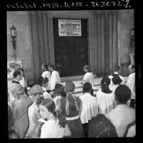 Members of Los Angeles' St. John's Episcopal Church at church door where a sign states "Closed for Duration of the War," 1970