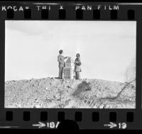 Couple on Bunker Hill pretending to touch top of Los Angeles City Hall, Calif., 1973