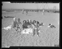 Eight girls lying in the sand while tanning with jetty in the background at Cabrillo Beach, Calif., 1947