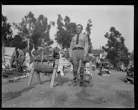 Boy Scout leader stands next to a sawhorse animal at a camping event in a park, circa 1935