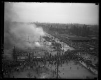 Overhead view of crowds surrounding the Los Angeles Auto Show grounds as smoke rises from the remains of the tents, 1929