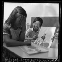 Duane Wong showing Maedon Law a card he made at Elysian Heights School in Los Angeles, Calif., 1966