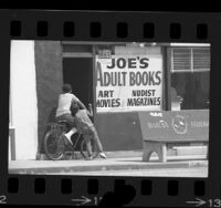 Two young boys peeking into doorway of an adult book store in Lennox, Calif., 1969