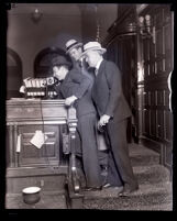 Defendents Dave Getzoff and Ben Getzoff with defense attorney Al McDonald in a courtroom, Los Angeles, 1929