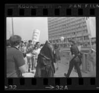 Protester wearing a black hood and robe outside of Century Plaza Hotel, where President Johnson is scheduled to arrive, 1967