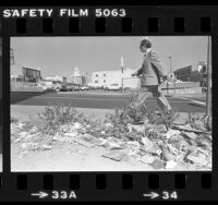 Man walking past lot covered with litter and weeds in Los Angeles, Calif., 1980