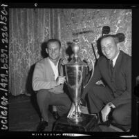 Race car driver Parnelli Jones and Payton Cramer with Los Angeles Times Grand Prix trophy, 1964