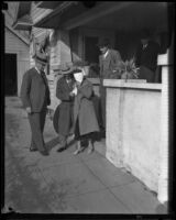 Kidnap victim Mary B. Skeele, blindfolded with detectives, outside the bungalow house where she was held, Pasadena, 1933