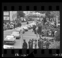 Procession of cars following hearse carrying body of Robert F. Kennedy driving down crowd lined street in Los Angeles, Calif., 1968