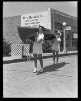 Barbara and June Murphy carrying a canoe to the Tournament of Lights, Balboa peninsula (Newport Beach), 1935