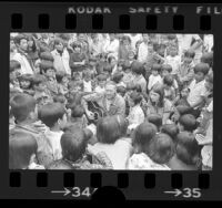 Gunnery Sergeant John Long playing guitar and surrounded by Cambodian refugee children at Camp Pendleton, Calif., 1975