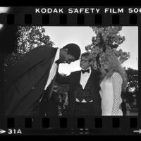 Earvin "Magic" Johson speaking with Bo Hopkins and an unidentified women at a City of Hope party at Pickfair honoring Jerry Buss, Beverly Hills, 1981