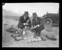 Two men examining kit of dynamite and wire found during sabotage incidents of Owens Valley Aqueduct, Calif., circa 1924