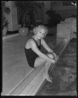 Dorothy Poynton, Olympic diver, posing seated at the edge of a swimming pool, 1932