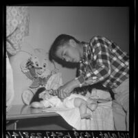 5th grade boy pinning diaper on baby doll in family life class at Steele Elementary School, Torrance, Calif., 1965