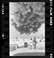 Nonprofit group handing out balloons printed with "The Process…" at Santa Monica Beach, Calif., 1979