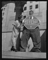 Henry Rohwer, also known as Happy Hi, holding a stop sign as punishment for a traffic violation and standing next to Lillian Brill, Los Angeles, 1935