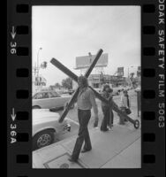 Reverend Arthur Blessitt walking along the Sunset Strip at Larrabee St. with his wheeled cross, Calif., 1977