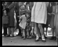 Father supporting toddler on the route of the Tournament of Roses Parade, Pasadena, 1932