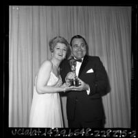 Comedian Jonathan Winters and actress Angela Lansbury posing with an Oscar at the 1965 Academy Awards