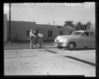 Lt. R. W. Cooley shows new treadles on highway which, when tripped by car operates signal in Santa Monica, Calif., 1948