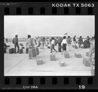 PSA passengers milling about on runway waiting to board plane after bomb search in Los Angeles, Calif., 1986