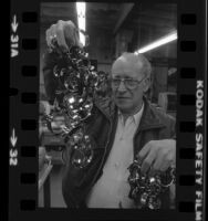 Engraver, Jack Zeider holding up string of bracelets honoring American hostages in Iran, Santa Monica, Calif. 1980