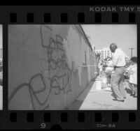 City councilman, Nate Holden helping to paint over graffiti covered wall in Los Angeles, Calif., 1989