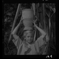 Kristen Commons, University Elementary School pupil, carries mortar on her head, 1958