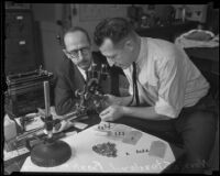 Criminologist Frank Gompert inspects a pistol while Norris Stensland watches, [Los Angeles], about 1931