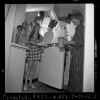 Grace and Neill Studley in their kitchen that's decorated with restaurant menus in Los Angeles, Calif., 1970