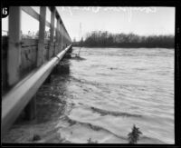 Los Angeles River and a wooden bridge during rainstorm flooding, Compton, 1927