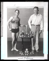 Junior Olympian Tony Galasso and his coach Ted Burns posing with trophies, Los Angeles, 1928