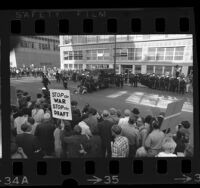 Draft protesters sitting in front of police van, as police and others watch outside Army Induction Center in Oakland, Calif., 1967