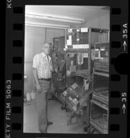 Thomas Amaral, standing besides damaged cages of the City of Hope National Medical Center's animal facility in Duarte, Calif., 1984