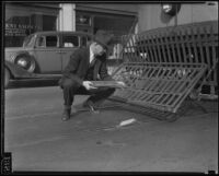 Inspector holds metal rod meant to derail street car, Los Angeles, 1934