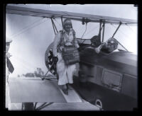 Edith Weber on the wing of an airplane with two men in pilot seats, Los Angeles, circa 1931