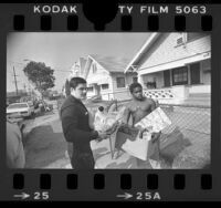 Police officer Jose Najera delivering Christmas package to Dennis Crump in Los Angeles, Calif., 1979