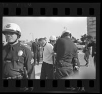 Man arrested as press watch outside of Century Plaza Hotel prior to demonstration during President Johnson's visit. B. 1967