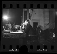 Councilman Gilbert Lindsay watching dentist Jack D. Gaynor take sodium fluoride capsules during fluoridation hearing in Los Angeles, Calif., 1966