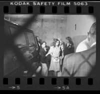 Patty Hearst in handcuffs, escorted by two women at inmate entrance of Criminal Court Building in Los Angeles, Calif., 1976