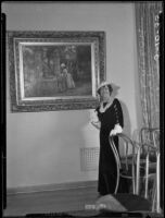 Hersee Moody Carson standing next to a painting attributed to Marie-François-Firmin Girard titled "Woman at the Well," Los Angeles, 1935