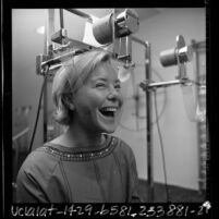 Woman demonstrating double chin electric massage machine, Los Angeles, Calif., 1966