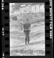 U.S. Army ordnance specialist carrying World War II shell from construction site in Tujunga, Calif., 1979