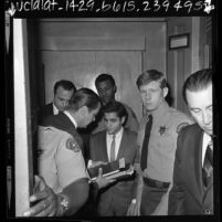 Sirhan Sirhan surrounded by sheriff deputies and lawyer Michael A. McCowan, Calif., 1969