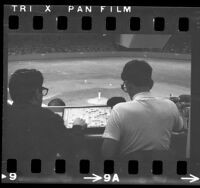 Los Angeles Dodgers game viewed over the shoulders of two reporters playing Scrabble, 1968