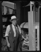 Charles M. Fuller stands next to his gold dredging invention with a cigar in his mouth, Bakersfield, 1935