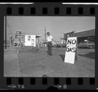 Kaz Hirata standing outside his gas station with "No Gas" signs written in English and Chinese in Los Angeles' Chinatown, Calif., 1974