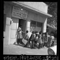 Teacher's aide greeting African American students at the door of a church converted into a "Freedom School" in San Bernardino, Calif